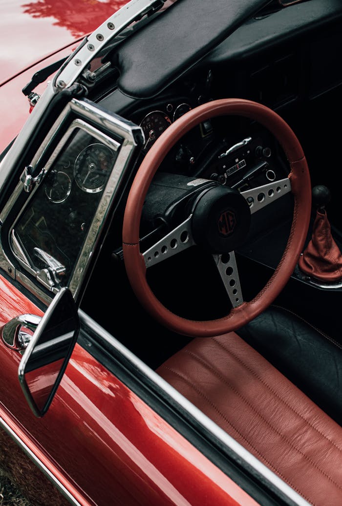 our-services-3 Close-up view of a vintage red convertible's interior showcasing a classic steering wheel and leather seats.