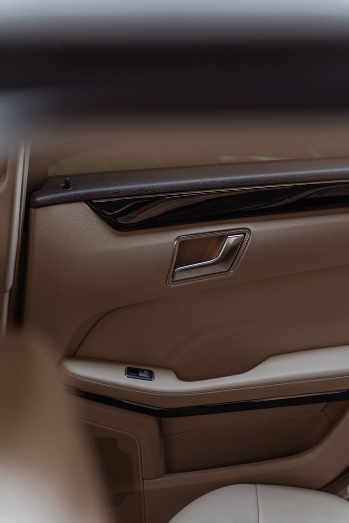 our-services-2 Close-up of a modern tan leather car door interior with elegant design.